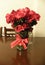 A bouquet of red roses in a glass vase with a red bow on a wooden table