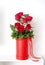 The bouquet of red roses is in a handmade red box. A rose arrangement is a beautiful gift for a loved one. Behind the bouquet is a