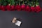 Bouquet of red roses and opened brown jewelery box on black background, with copy space, top view