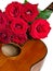 Bouquet of red roses on top of classical guitar isolated