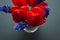 Bouquet of red tulips with blue muscari flowers on a textural dark background.