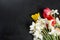 Bouquet of red tulips, daffodils and gift on the black background
