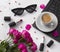 Bouquet of roses, cup of coffee, laptop, sunglasses and lipstick on white table.