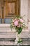 Bouquet of roses, hydrangeas and ivy stands on a small column on the stone steps of the church