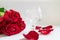 Bouquet of roses, rose petals and brandy glass on white background