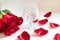 Bouquet of roses, rose petals and brandy glass on white background