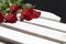 Bouquet of scarlet roses. Five flowers lie on a wooden box. On a black background
