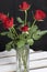 A bouquet of scarlet roses in a glass vase. Five flowers. On a black background