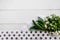 Bouquet with small white flowers, long green leaves, white lace, white polka dot fabric on a white wooden background