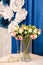A bouquet of small white and pink roses in a transparent veil. golden beads Blue background
