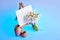 Bouquet of snowdrops and a small easel with a white paper and mini jars on a blue background