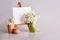 Bouquet of snowdrops and a small easel with a white paper and mini jars on a grey background