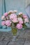 A bouquet of soft pink peonies sitting on a cement floor