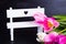 Bouquet of tender pink tulips with white bench on black wooden b