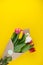 A bouquet of tulips wrapped in craft paper. Spring flowers. Gift delivery. Celebration. Copy space. Yellow, white, pink, purple