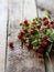 A bouquet of twigs of ripe wild strawberries with leaves on rustic wood background. copy space, selective focus