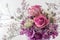 Bouquet of two pink roses and different purple and white flowers on white background