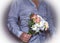 Bouquet with white Daisy flowers in the man`s hand in shirt on white background.