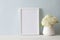 A bouquet of white hydrangea stands near the blue wall on a wooden table. A4 frame stands upright. Bundle.