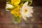 A bouquet of white lotuses and yellow water lilies on a wooden background in the sun with highlights and bokeh