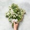 Bouquet white spring flower spirea in female hand on light background. Top view.