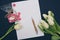 Bouquet of white tulips, blank sheet of paper, pen and lollipops on a black background, matte filter