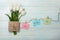 A bouquet of white tulips and envelope with a color stickers with clothespins on a rope and blue wooden boards . Mother`s day