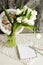 A bouquet of white tulips, next to a Notepad, pencils, and a stained-glass wall clock .