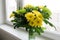 Bouquet of yellow chrysanthemums and green stands on windowsill
