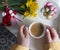 Bouquet of yellow daffodils with red and white martenitsa and a woman's hand holding a cup of coffee