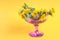 Bouquet of yellow dandelions in a lilac vase on a yellow background, space for text