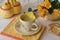 Bouquet or yellow and orange roses with mug or cup of coffee, tea or cappuccino. Concept of starting a working day or a