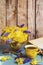 Bouquet of yellow primroses and muscari in a vase. Wooden background, book, yellow cup.