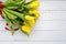 Bouquet of yellow tulips flowers on white wooden background. Waiting for spring. Happy Easter card, mother`s day, March 8. Flat