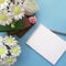 Bouquets of soap flowers, blank notepad with pencil, books on light blue background.