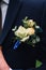 boutonniere with a white rose on the lapel of the groom& x27;s blue jacket