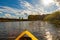 Bow of bright yellow canoe paddling on river surrounded by fores