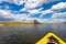 Bow of bright yellow canoe paddling on river surrounded by fores