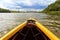 Bow of bright yellow canoe paddling on river surrounded by fores