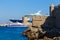 Bow of large cruise ship in the port of the ancient city, protruding from behind the fortress and tower of the ancient Fort. The