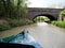 The bow of a narrowboat about to pass under a bridge