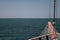 The bow of the ship against the sea horizon with a grid, steel cables and a folded sail.