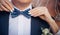Bow tie on the groom`s suit. Bride`s hands touch the tie of her betrothed, close up. Theme of the wedding, newlyweds, love