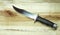 Bowie hunting knife on a wooden background. Combat army knife made of high- quality stainless steel. Weapons of attack and defense