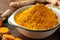 Bowl with aromatic turmeric powder on table, closeup