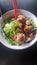 a bowl of asian food leeks and meatballs with chopsticks on a table