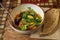 Bowl with baked eggplants, tomatoes, arugula leaves on table. Piece of rye bread. Vegan and diet concept