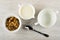 Bowl with baked muesli, pitcher with yogurt, empty bowl, spoon on wooden table. Top view