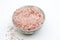 Bowl of bath salts with pink grains, spoon, isolated,frontal view