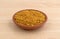 Bowl of bee pollen granules on a wood table